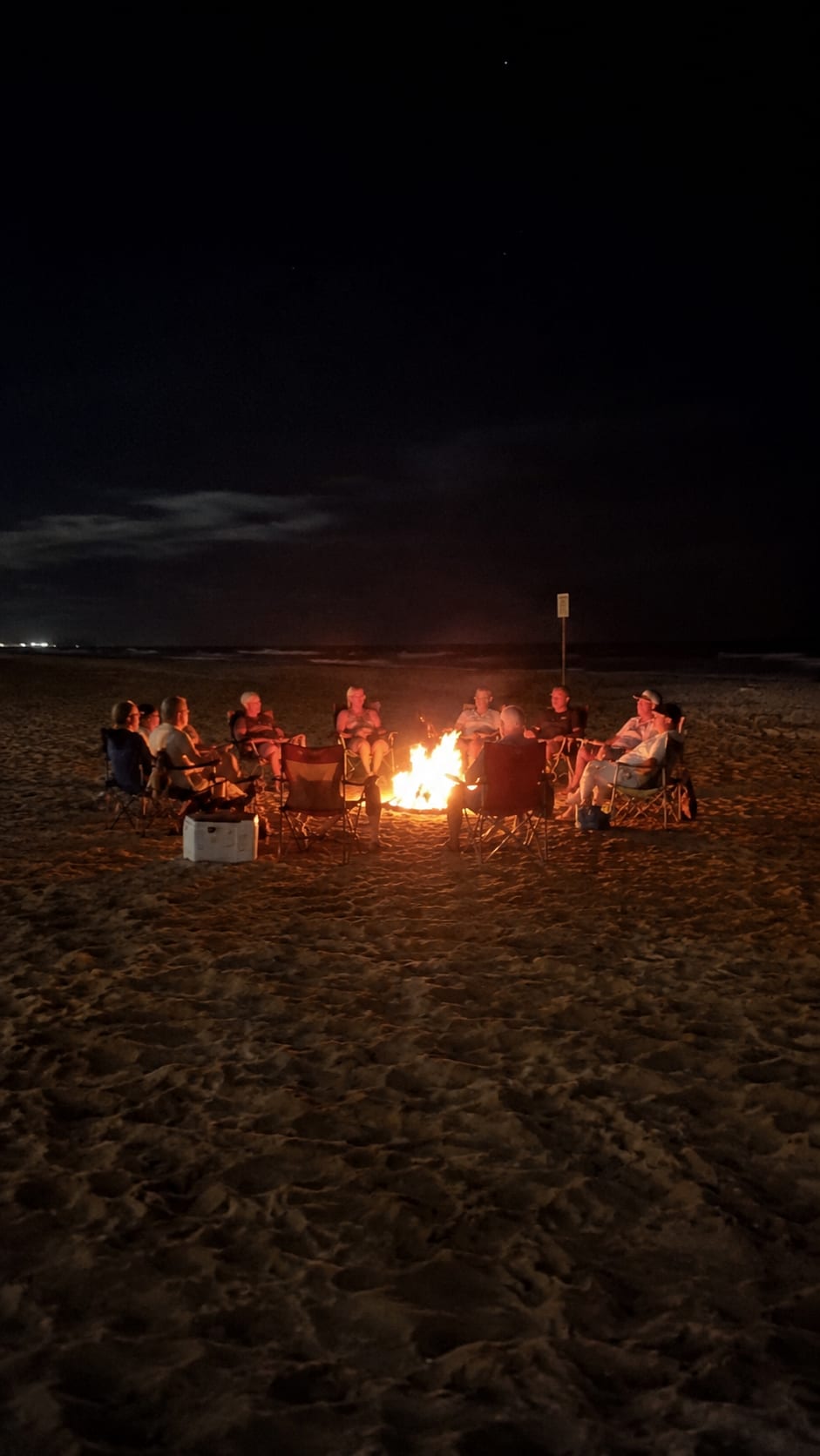 A private beach bonfire after dark, set and waiting